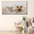 Rectangular canvas with cream and brown tones; Image of two highland cows in natural setting; Slim, light-coloured frame; Canvas texture visible on surface;
