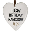 White ceramic heart shape; Black text 'HAPPY BIRTHDAY HANDSOME'; Gold heart and cross design; Brown hanging strap; Smooth matte finish;