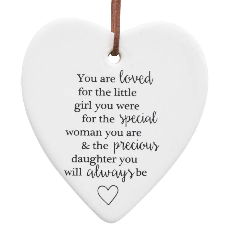 white ceramic heart shape; black printed text message on front; small heart graphic at bottom; suede hanging cord attached at top;