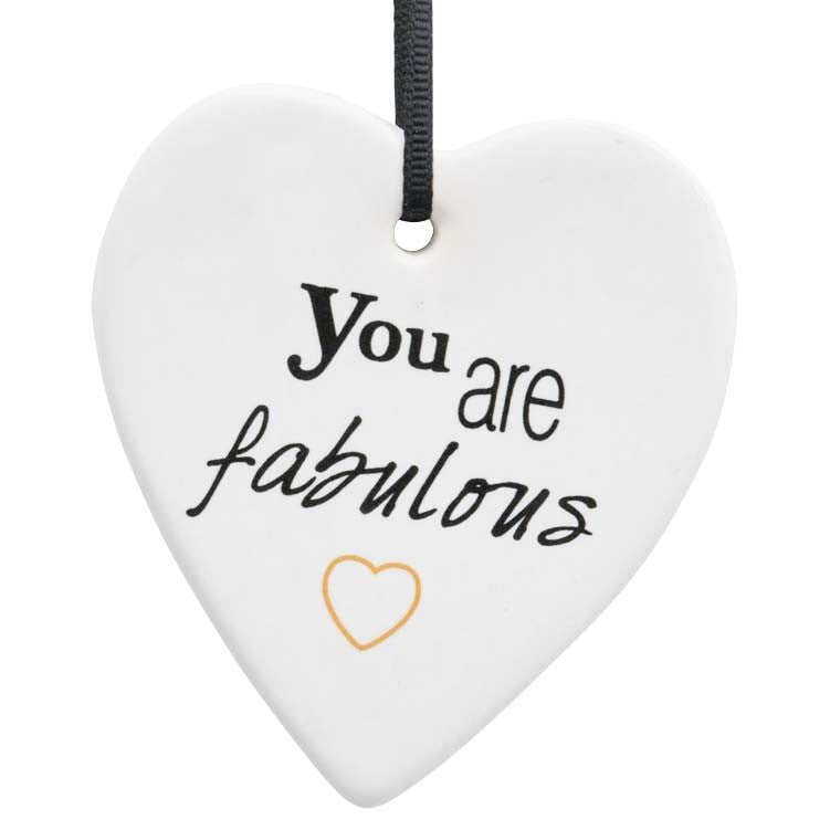 White ceramic heart shape; Black ribbon hanger attached; Handwritten style black script text; Small gold heart detail below text;