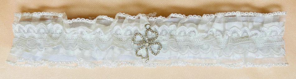 Ivory colour lace; Ruffled lace design; Small clover-shaped charm with rhinestones; Elasticated band;