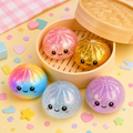 Five round dumpling-shaped squishy toys with kawaii faces; Random assortment includes glitter, translucent, metallic, pastel, and rainbow finishes; Round bamboo-steamer-style mystery packaging;
