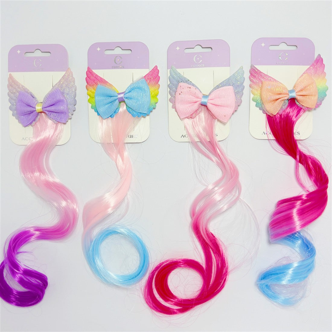 Long wavy synthetic hair strand attached to clip; Angel wing shapes behind a central bow; Mixed pastel and bright rainbow colours; Carded retail packaging with hanging slot;