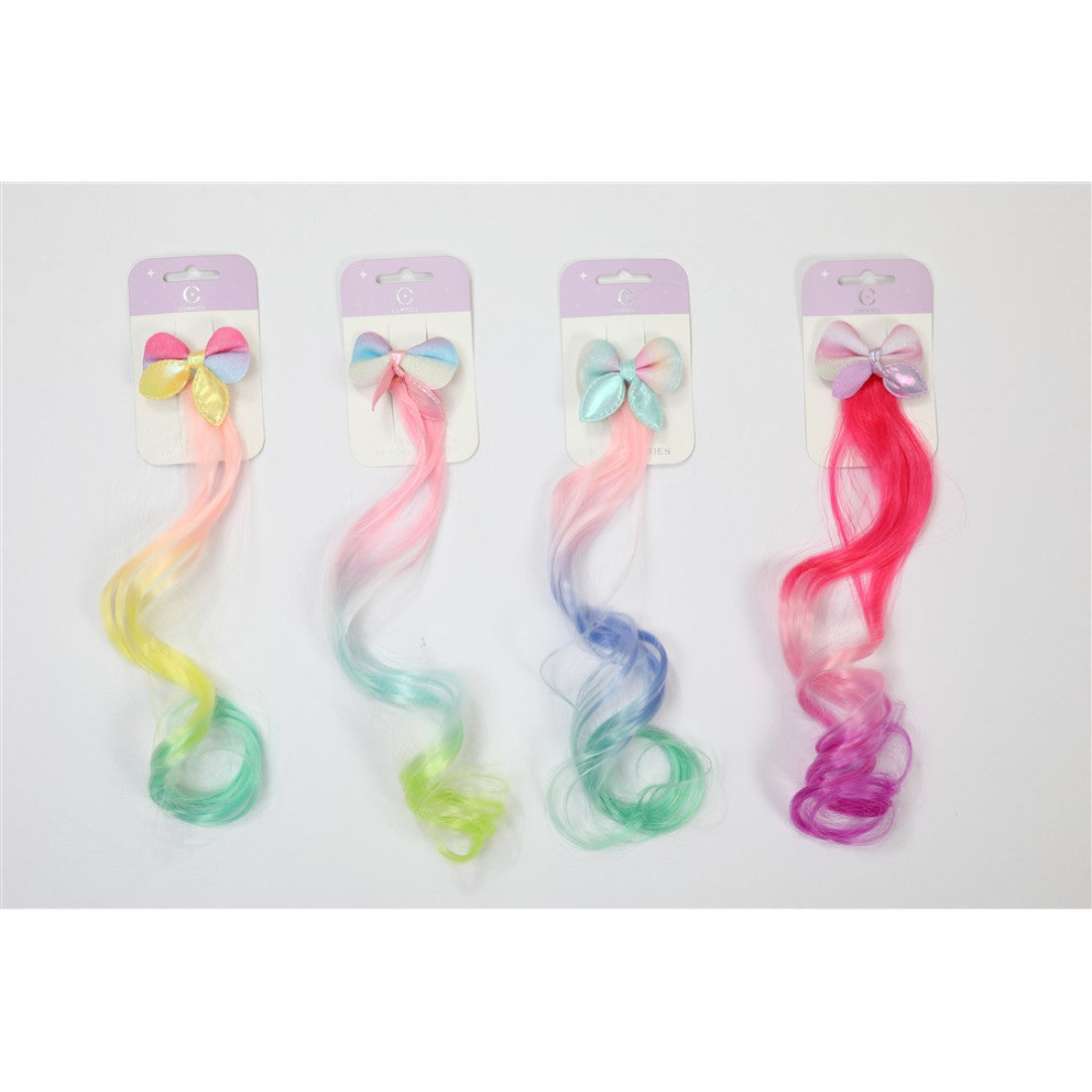 Long curly synthetic hair extension; Gradient pastel and bright colours including pink, yellow, green, blue and purple; Large bow clip at the top in matching pastel shades; Mounted on simple branded display card;