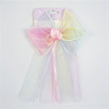 Large pastel gradient bow with pink, yellow and blue tones; Long sheer veil attached behind the bow; Pink satin knot at the centre of the bow; Thin pink and white ribbon tails hanging from the centre; Packaged on a light pink backing card;