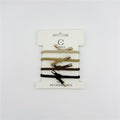Four elastic hair ties on a white backing card; Neutral colours including beige, tan, brown and black; Knotted design at the centre of each tie; Small metallic tube ends on each tie;
