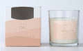 Clear glass jar; Peach-coloured label with gold text; White candle wax; Box packaging with peach gradient design; Single white wick;