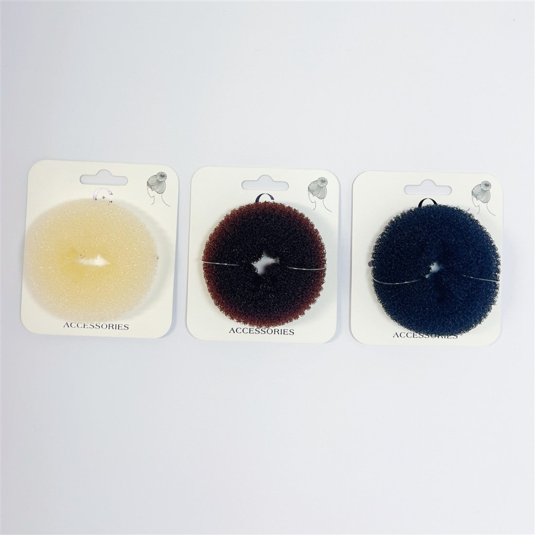 Round donut-shaped hair sponge; Medium-sized ring with central hole; Shown in light, brown and dark colours; Each piece displayed on white accessories card;