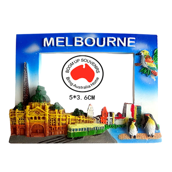 Rectangular frame shape; Blue top background with MELBOURNE text; 3D landmarks including buildings and trams; Penguins and a multicoloured bird on right side; Bright, multicoloured design;