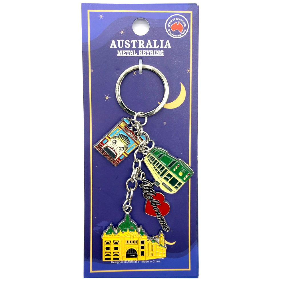 Set of four metal keyrings on a purple card; Keyrings depict Melbourne landmarks including Flinders Street Station; Includes a green tram and a red heart with 'Melbourne' text; Keyrings are colourful with enamel detailing; Packaged on a card labelled 'Australia Metal Keyring';