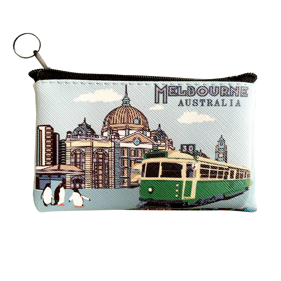 Light blue coin purse with printed Melbourne cityscape; Green tram and building illustration on front; Black zip closure with metal keyring pull; Textured fabric material;