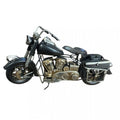 Black metal motorcycle model with metallic engine details; Classic cruiser style with curved handlebars; Rear storage box and side frame details; Visible springs on front fork and spoked wheels;