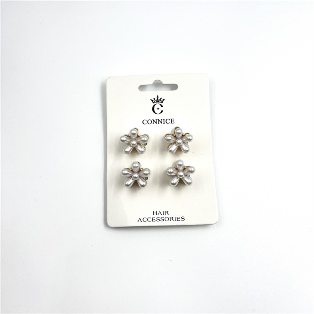 Four small flower-shaped hair clips on a branded backing card; White pearl-look beads forming each flower petal; Gold-toned metal visible at the base of the flowers; Simple white card packaging labelled as hair accessories;