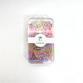 Clear plastic storage box with rounded corners; Box label printed with the brand name "CONNICE" and a crown logo; Assorted pastel hair elastics in pink, purple, yellow, green and blue tones; Compact, rectangular packaging with hanging tab at the top;