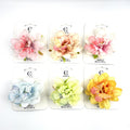 Artificial layered flower clip in pastel colours; 3D butterfly print on some petals; Mounted on white branded backing card; Various soft shades including pink, peach, blue, green and yellow;