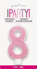 pink glitter number 8 shape; white candle base; packaged on white card with 'unique PARTY!' branding; approximately 8cm tall; glitter finish on numeral;