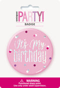 Pink round badge; Glitz silver text saying 'It's My Birthday'; Confetti dot pattern in multiple colours; Plastic material; Retail card packaging with warning label;