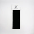 Black wide fabric strip styled as a headband; Presented on a white branded backing card; Plain, unpatterned design; Rectangular shape suggesting 7cm wide band;