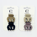 Two cards, each holding two small claw clips; Matte finish plastic in neutral tones (beige, tan, navy, taupe); Rounded three-prong claw shape; Mounted on white branded backing cards with hang holes;