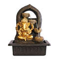 Golden Ganesh statue seated at the front of the fountain; Dark stone-look arch backdrop with leaf-like pattern; Tiered bowl water feature with flowing water streams; Rectangular black base reservoir with moulded detailing;