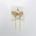 Gold-tone butterfly-shaped claw clip; Wings decorated with iridescent rhinestones; Two long gold chains hanging from the clip; Pearl-like beads at the ends of the chains; Mounted on branded hair accessories card;