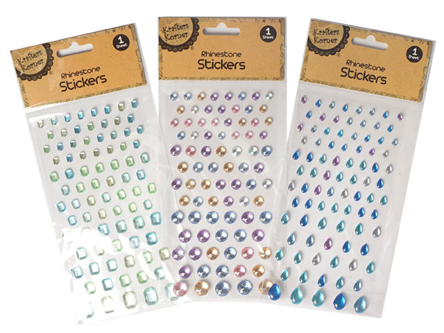 single sheet packaging; assorted rhinestone shapes including round, teardrop, rectangular; various colours including blue, green, purple, clear, amber; self-adhesive stickers visible on transparent backing;