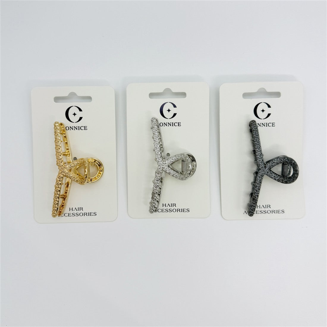Slim metal hair claw clip in a cross-like rose shape; Set shown in metallic gold, silver and dark grey finishes; Clips presented on white branded backing cards; Text on card reads “HAIR ACCESSORIES” at the bottom;