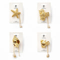 Gold-tone metal hair claws in various shell and starfish shapes; Each claw includes fine gold chains with dangling charms; Charms include small shells, starfish and faux pearls; Items are carded on branded CONNICE hair accessories backing;
