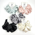 Shiny satin fabric with smooth texture; Scrunchies shown in solid colours including black, cream, pink, grey and light green; Chunky, gathered design for a full look; Each scrunchie displayed on branded CONNICE card packaging;