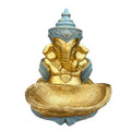Gold-coloured Ganesh figure with elephant head; Light blue decorative headpiece and clothing; Large gold textured dish in front of statue; Ornate detailing on jewellery and headband;