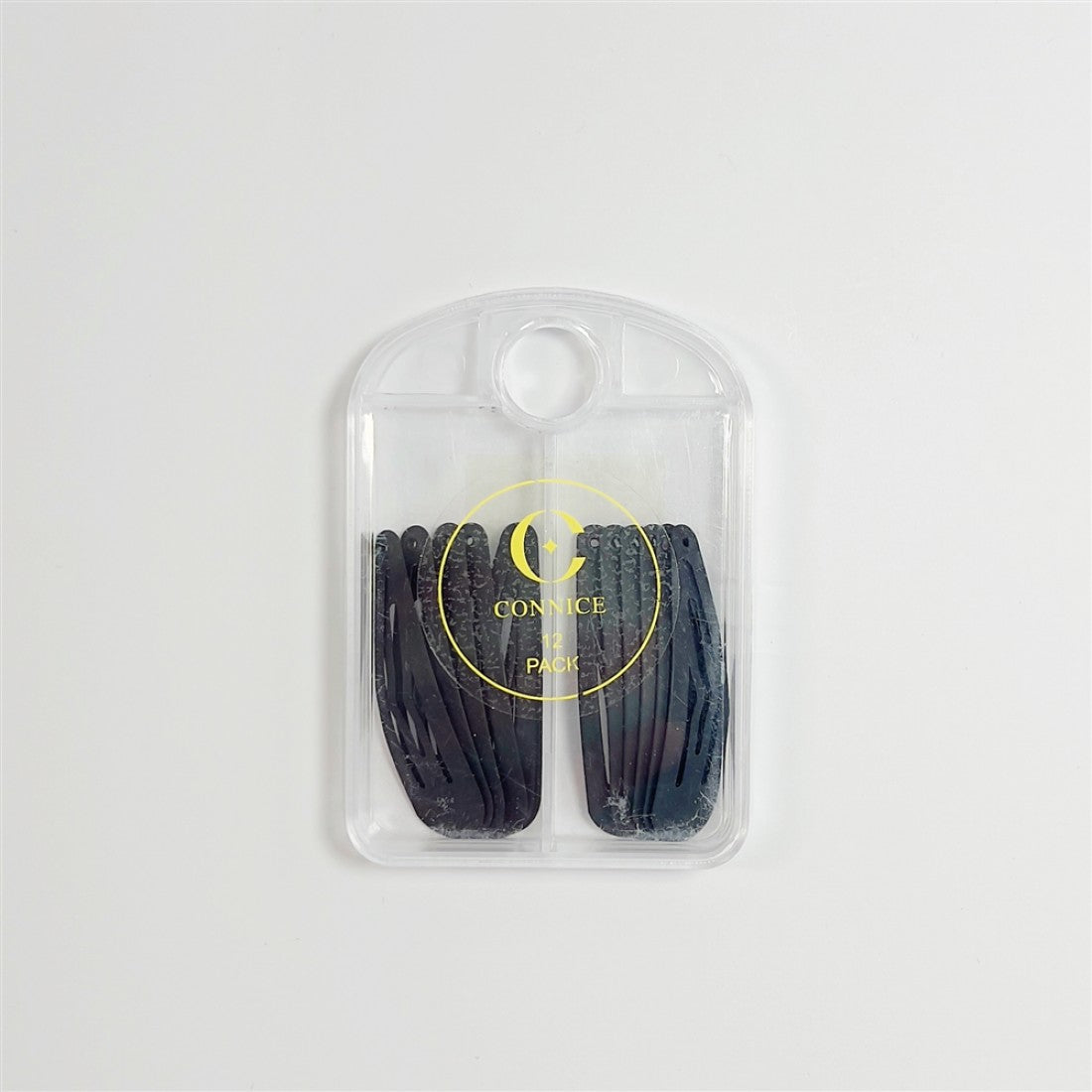 Matte black snap-style hair clips; Pack of multiple clips arranged in two rows; Clear plastic storage case with rounded top; Yellow printed branding and text on front of case;