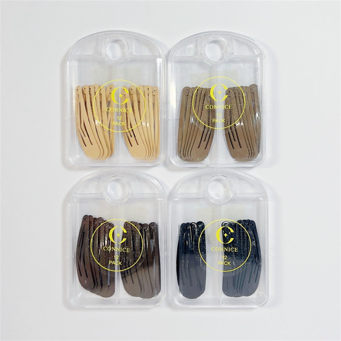 Four clear plastic cases each holding 12 snap-style hair clips; Clips in assorted neutral colours including beige, brown and black tones; Circular printed logo with text on each case; Cases have a rounded top with a hole for hanging or display;