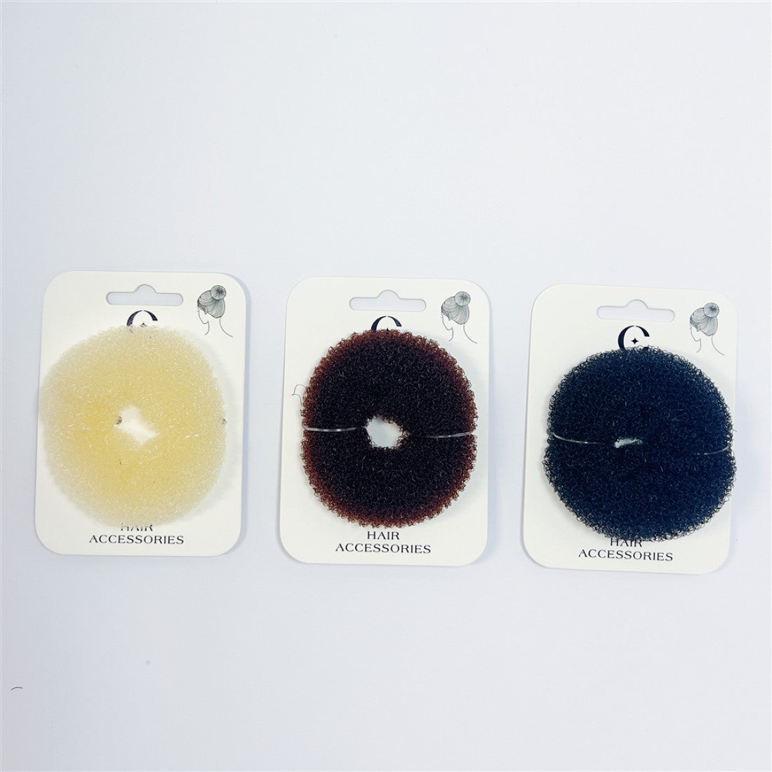 Three mesh donut hair rings shown: blond, brown and black; Round donut shape with central hole; Textured sponge-like material; Each piece displayed on white hair accessories backing card;