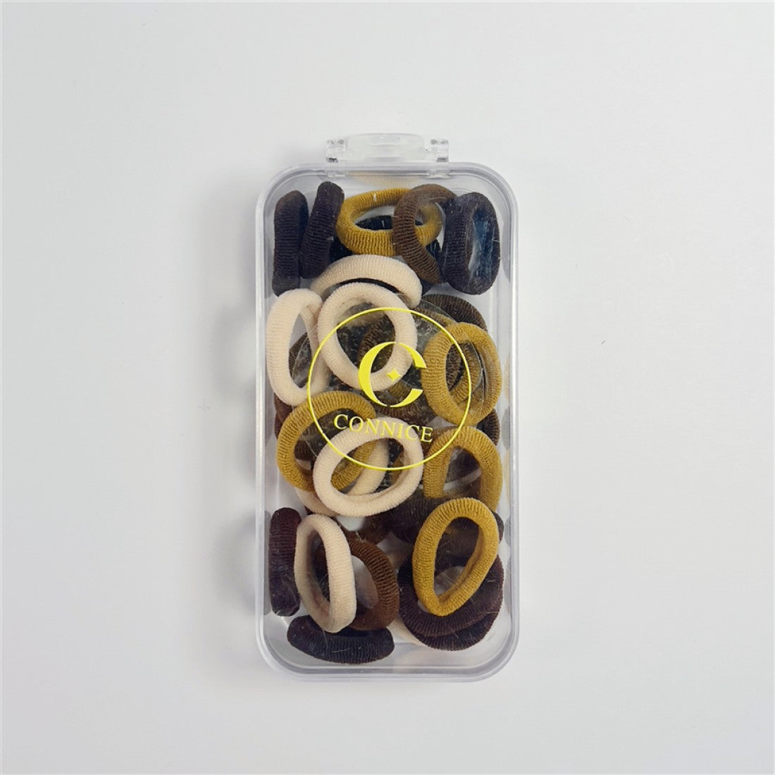 Pack of multiple small elastic hair ties; Mix of neutral colours including beige, brown and mustard tones; Soft, fabric-covered finish on each tie; Supplied in a clear rectangular plastic case with flip lid; Gold circular logo printed on the front of the case;
