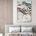 Graffiti style painting with colourful spray paint effect; Silver coloured frame surrounding the artwork; Rectangular shape with dimensions approximately 82.5x122.5x4.5cm; Wall hanging art displayed above a bed in a room setting;