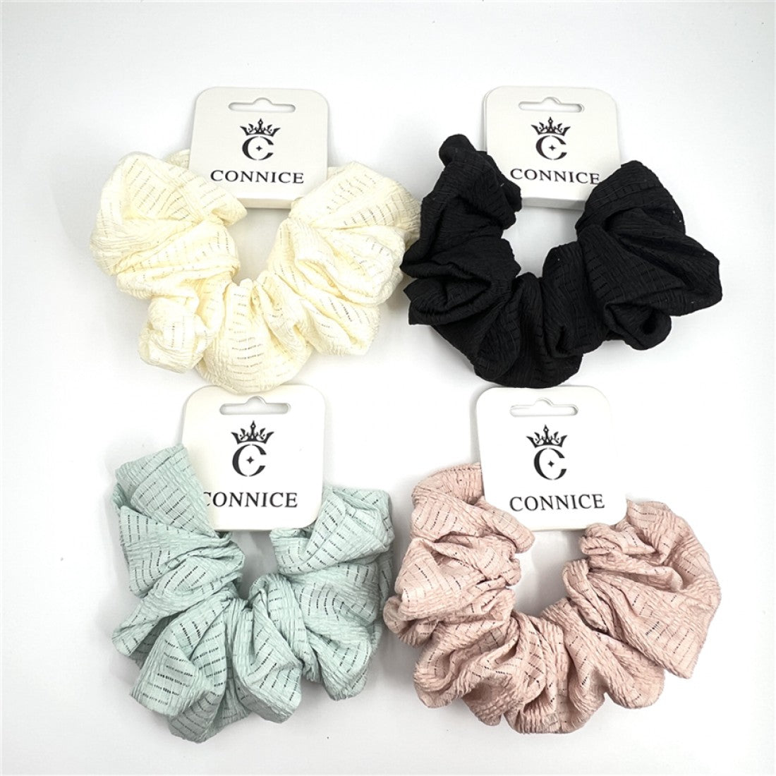 Large, gathered fabric scrunchie; Textured fabric with subtle linear pattern; Shown in soft muted colours including cream, black, mint and blush; Each scrunchie displayed on white branded backing card;