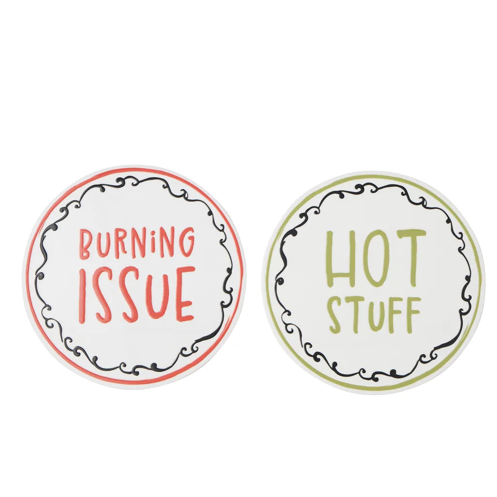 set of two round ceramic trivets; white base colour with black decorative border; one trivet with red text 'BURNING ISSUE'; one trivet with green text 'HOT STUFF'; each trivet approx. 20cm diameter;