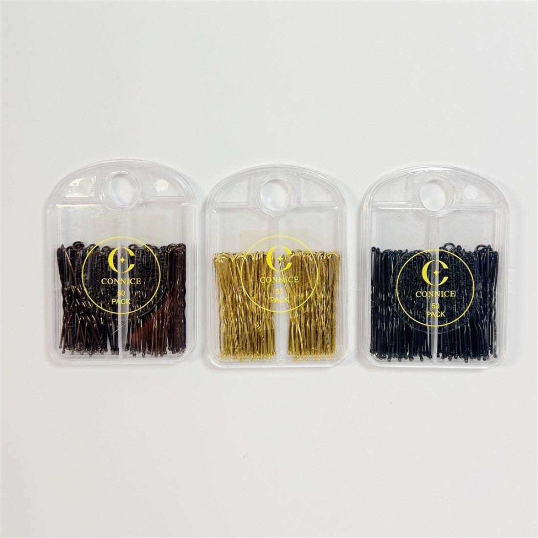 Three clear plastic cases each holding 50 U-shape hair pins; Pins visible in brown, gold and black colours; Round hanging hole at top of each case; Gold circular logo and text printed on front of cases;