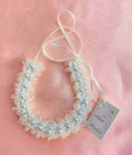 white lace with scalloped edges; pearls aligned along band; thin white ribbon tie; soft sheer fabric appearance;