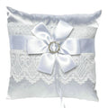 white satin square pillow; lace trim across the centre; white satin ribbon bow; jewel ring detail at bow centre;