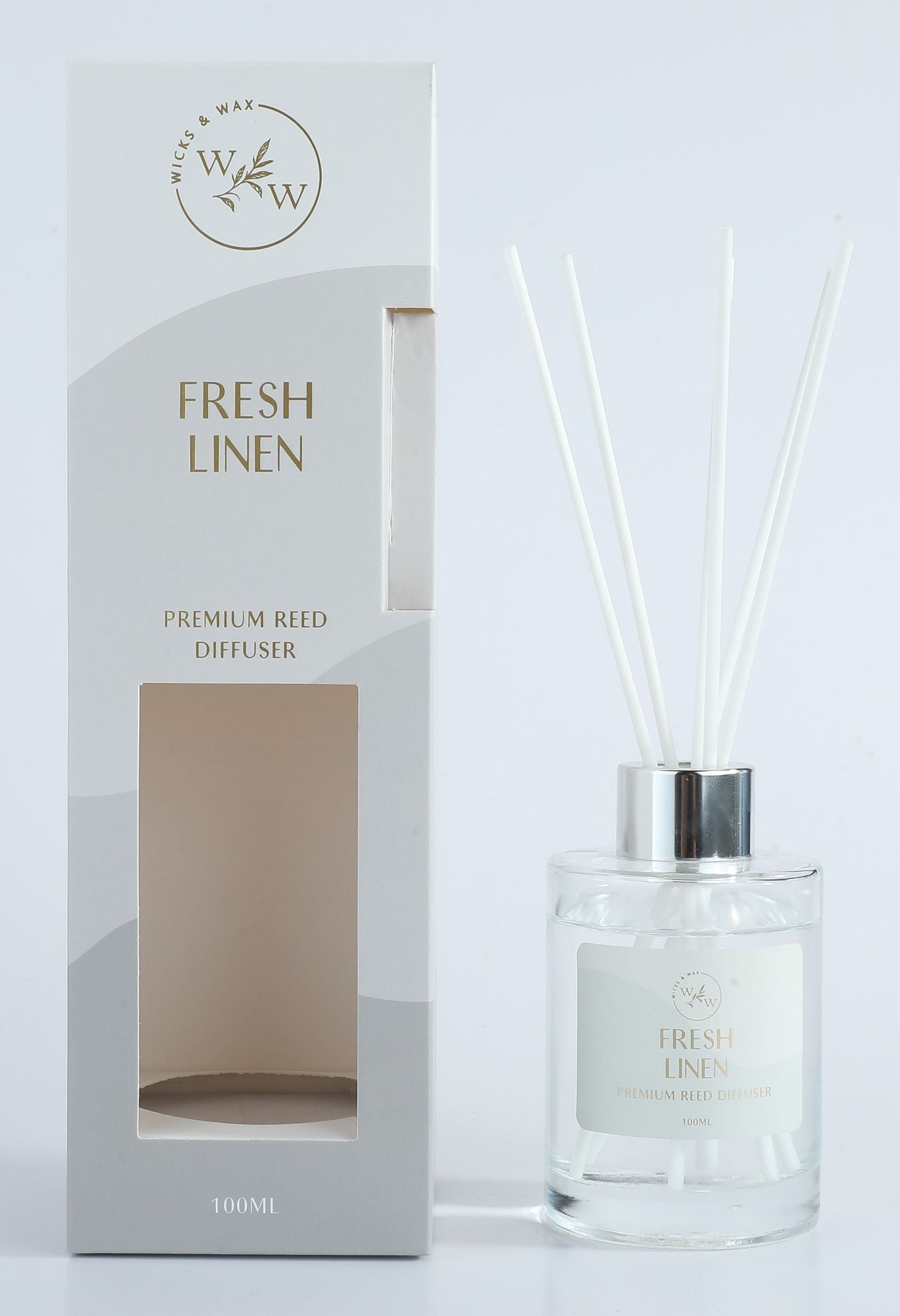 Clear glass bottle with silver collar; White diffuser reeds; Light grey and white packaging; Gold text on packaging and label;