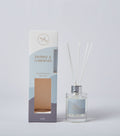 Clear glass bottle with silver cap; White reed sticks; Box with white, pale blue, and grey colour blocks; Gold coloured text on bottle and box;
