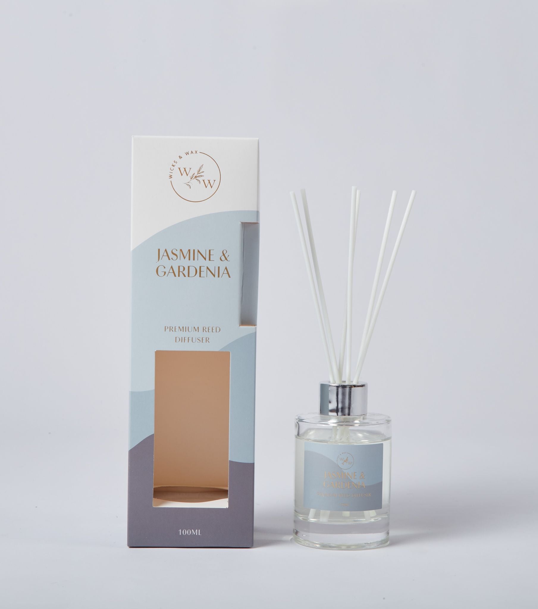 Clear glass bottle with silver cap; White reed sticks; Box with white, pale blue, and grey colour blocks; Gold coloured text on bottle and box;