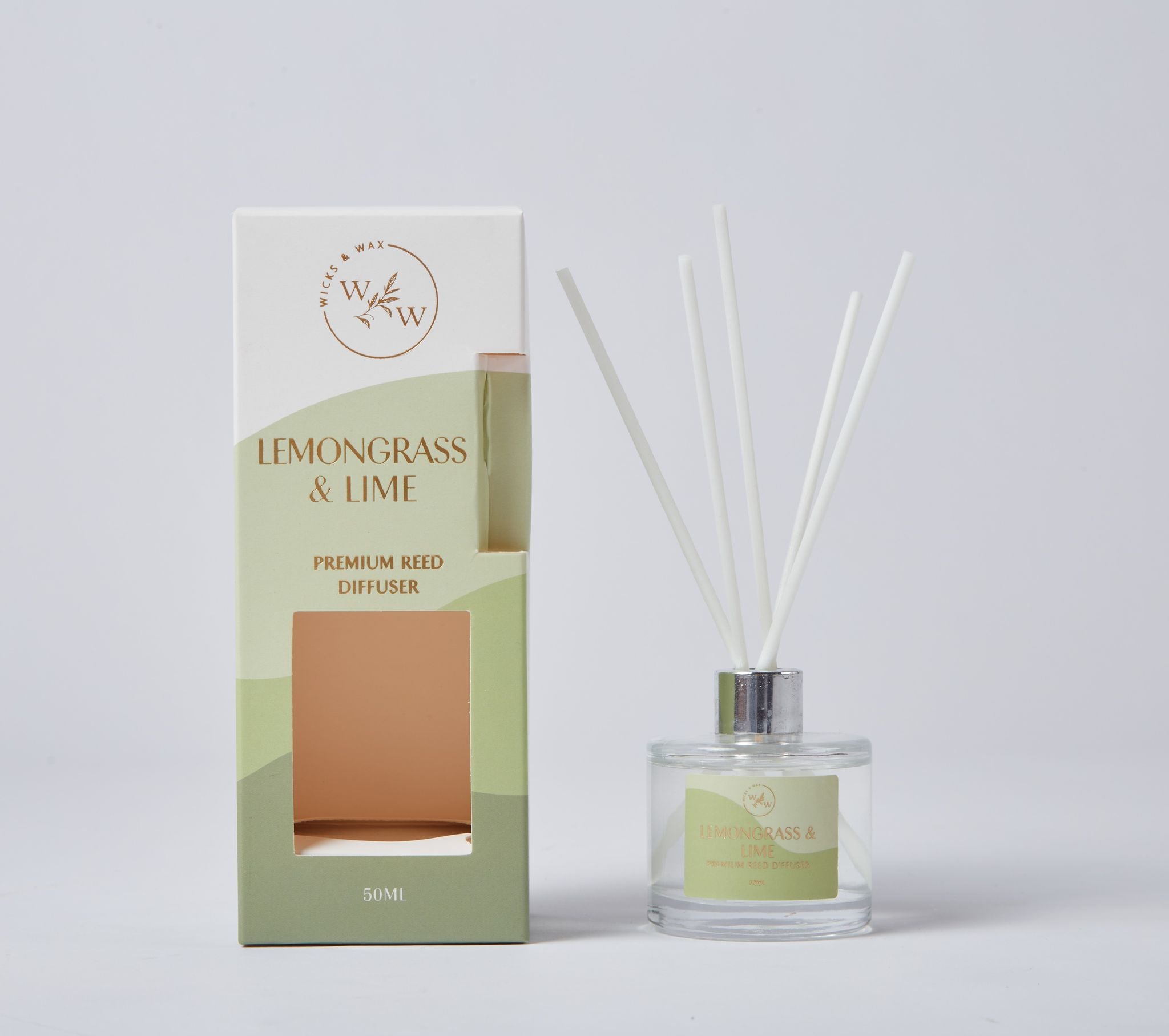 Clear glass bottle with light green label; Five white reed sticks inserted into bottle; Box packaging with gradient green and cream colours; Label and box text in gold colour;