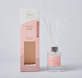 clear glass bottle with silver collar; pink label on bottle; white reed sticks; pink and white packaging box with window;