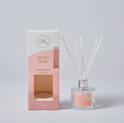 Clear glass diffuser bottle with silver collar; Light pink label with gold text; Set of five white reeds; Pink and white packaging box with gold text; Bottle contains clear liquid;