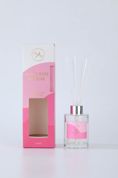 clear glass bottle; silver-coloured cap; white reed sticks; pink and white packaging box; gold foil text on packaging;
